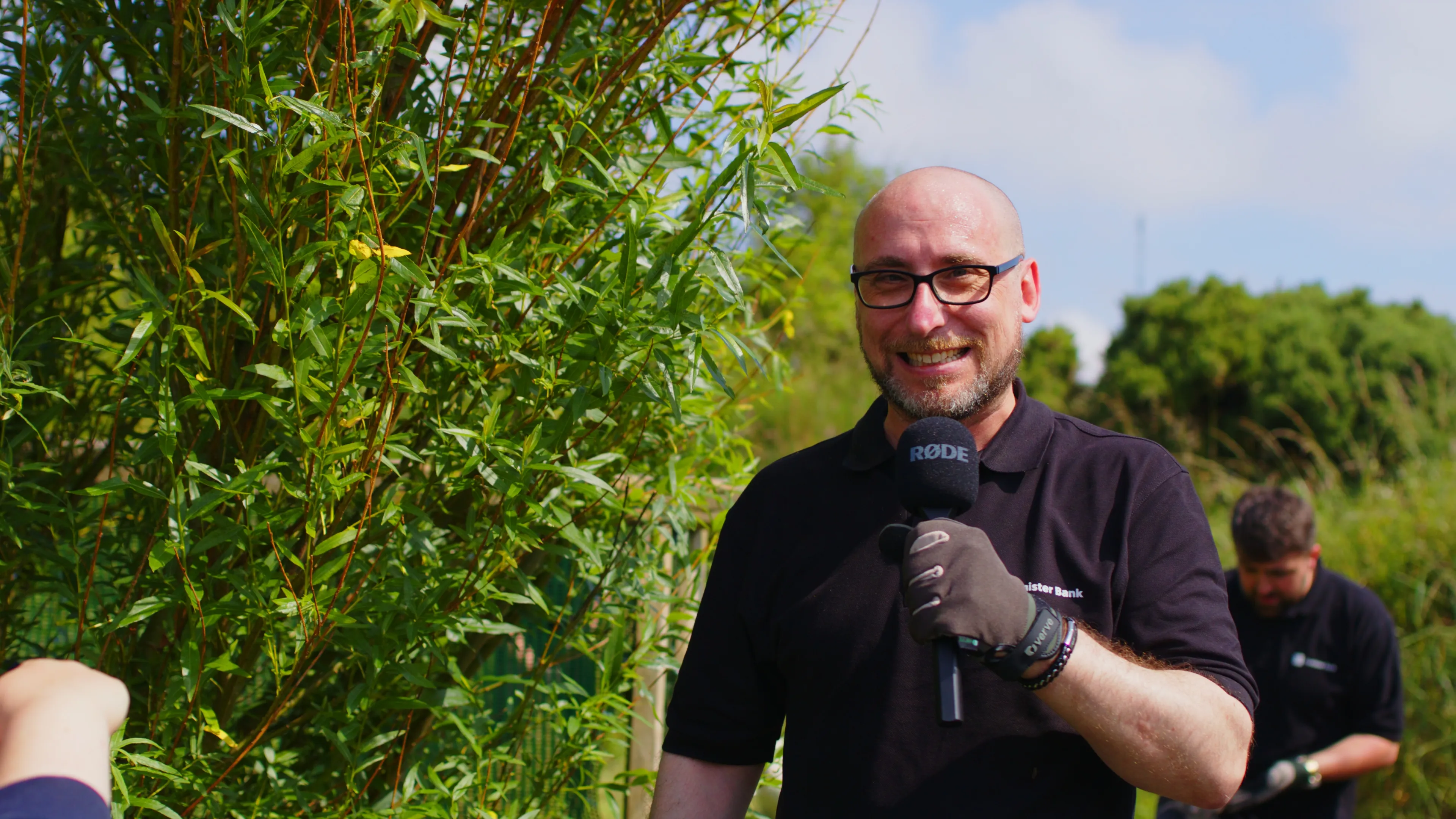 Conister Bank volunteers working among tall grass and vegetation during the bee safe garden project at The Children's Centre, Isle of Man, filmed by DotPerformance